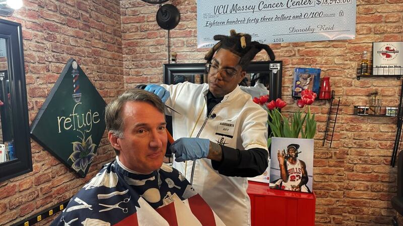 Dot Reid gives Gov. Glenn Youngkin a haircut at her Richmond barber shop after a bill-signing...