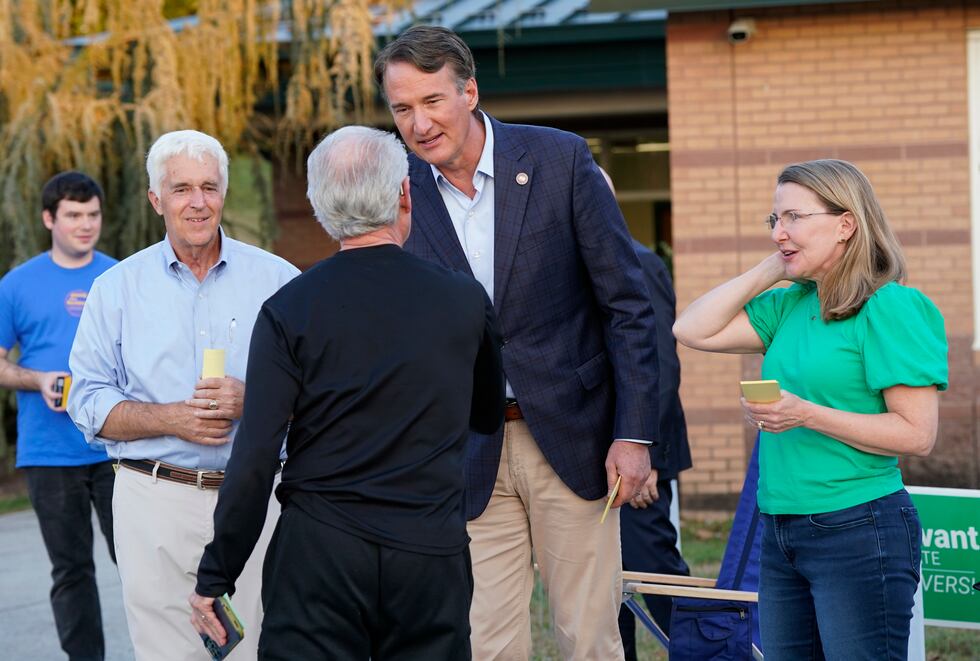 Virginia Gov. Glenn Youngkin, center, hands out sample a ballot to a voter along with Virginia...