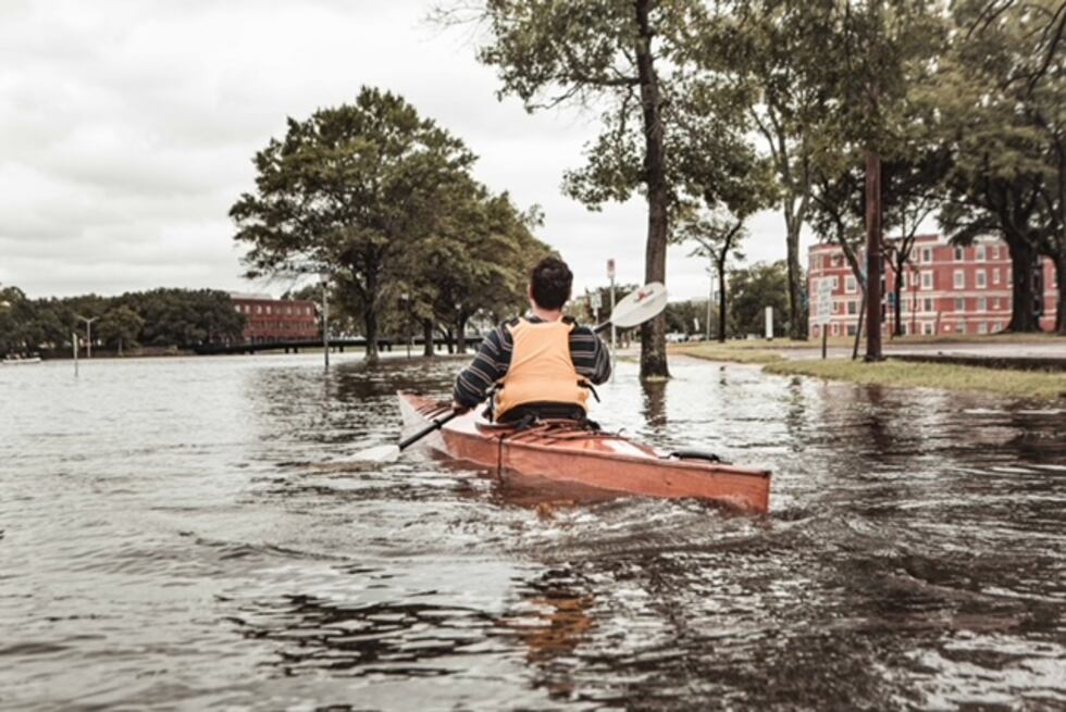 Man in kayak rowing down a flooded street in Norfolk in 2019