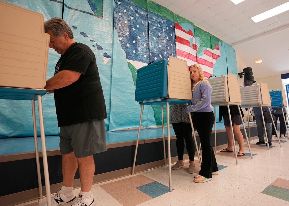 Voters cast their ballots in front of a mural at a Elementary school polling station Tuesday...