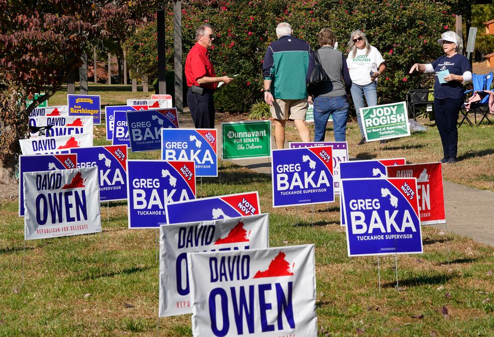 Volunteers hand out sample ballots as voters walk to a polling station Tuesday Nov. 7, 2023,...