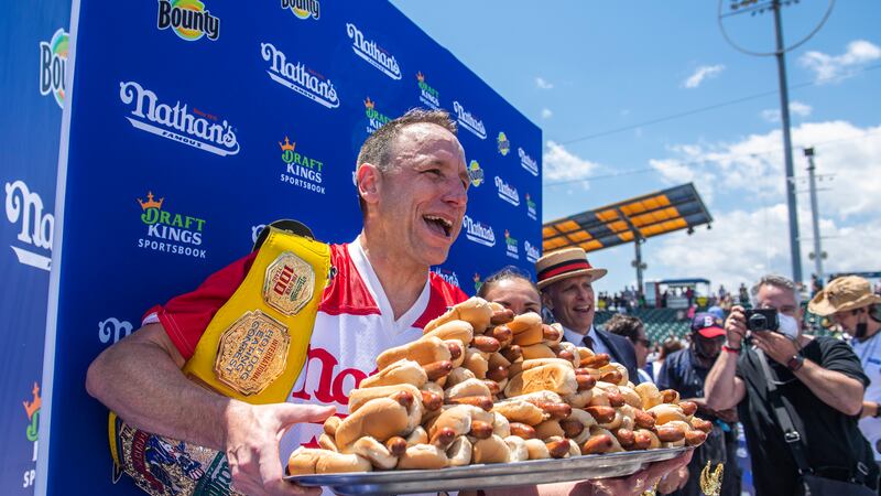 Winners Joey Chestnut and Michelle Lesco, obscured behind hot dogs, pose at the Nathan's...