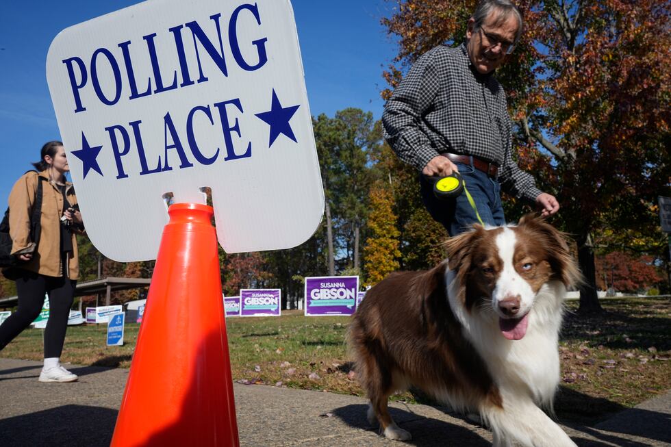 A voter leads his dog past a polling sign after voting at a polling station Tuesday Nov. 7,...