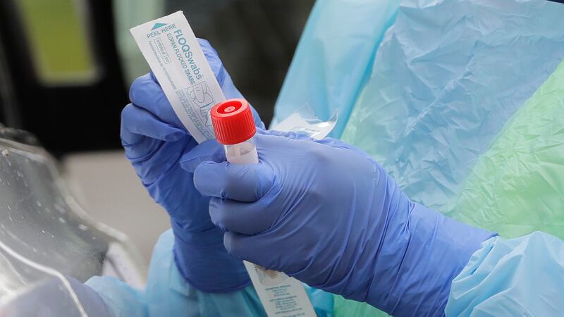 In this April 2, 2020 file photo, a nurse holds a vial and a swab at a drive-up coronavirus...